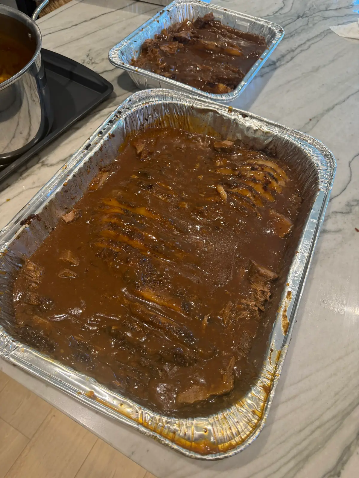 The sliced brisket arranged in the pan and covered with gravy